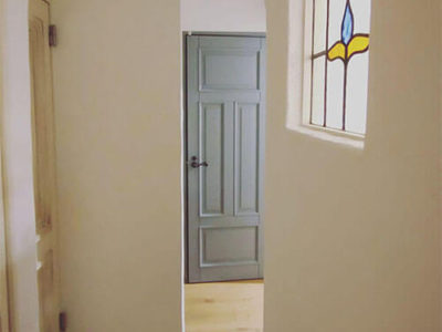ものづくりでつながるアトリエ。漆喰壁とパステルブルーの木製ドア。
